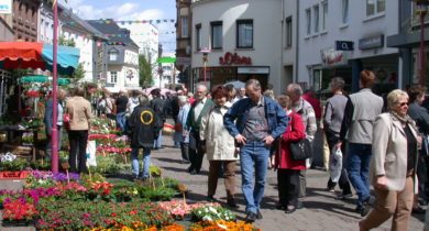 Blumenmarkt in der Innenstadt in Merzig mit vielen Passanten und Geschäften