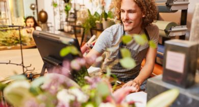 Junger Mann steht an der Kasse in einem Blumengeschäft
