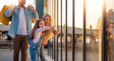 Familie beobachtet das Schaufenster während der Mann die Einkauftsüten hält