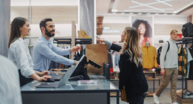 Eine Dame steht an der Kasse und zahlt ihren Einkauf im Kleidergeschäft